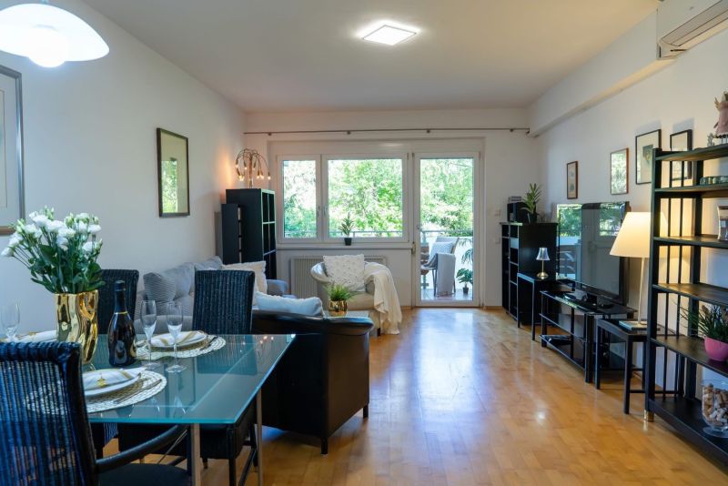 Living room of a three-room apartment with a wood-decor floor and a dining area.