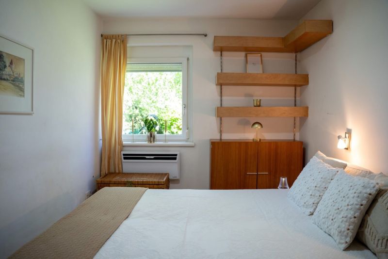 Bedroom in a 3-room apartment with shelves and a window with a curtain.