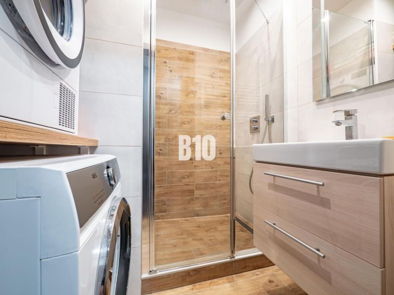 A bathroom in a studio apartment with a wooden decor floor and a shower corner.