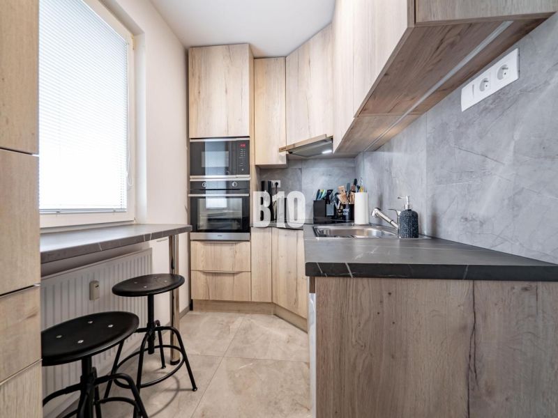 Compact kitchen with wood-patterned flooring, bright interior, equipment, and seating.