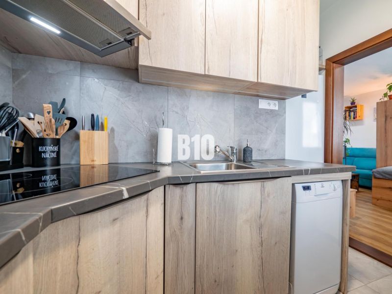 A kitchen with a wooden decor in a studio apartment, open transition to the living room.