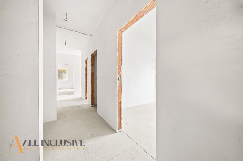 A hallway in a 3-room apartment with white walls and unfinished doors.