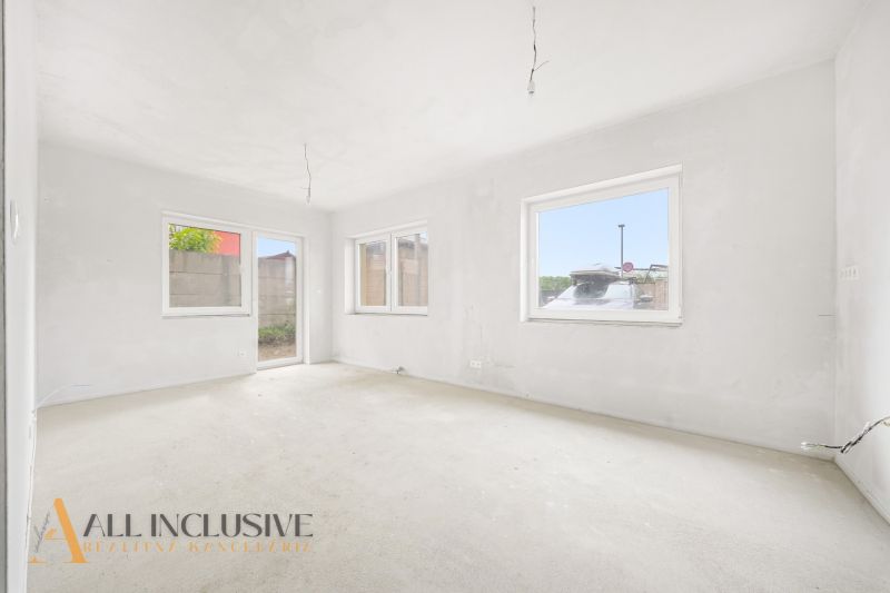 A spacious room with large windows in a 3-room apartment, white walls, unfinished floor.
