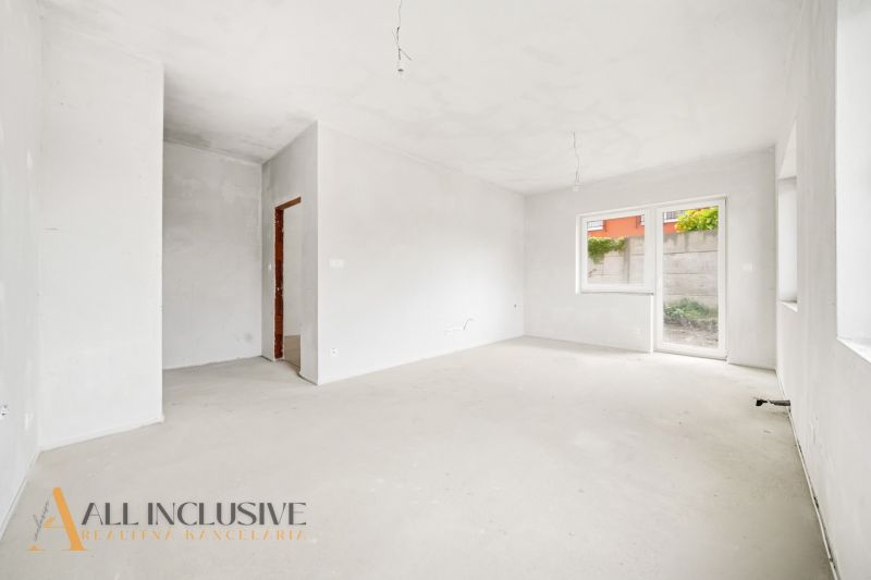An empty room in a 3-bedroom apartment with a window and access to the terrace.