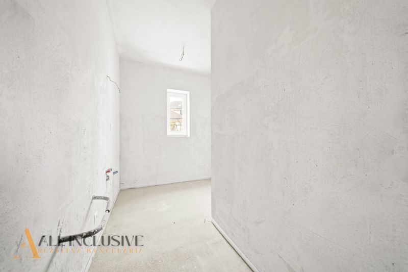 An unfurnished kitchen in a 3-room apartment with a concrete floor and a small window.