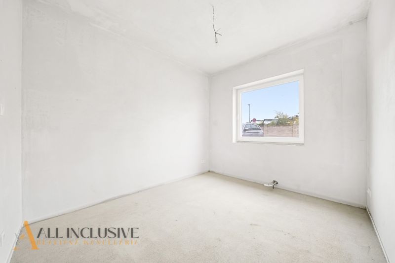 An empty room with a carpet and a large window in a 3-room apartment.