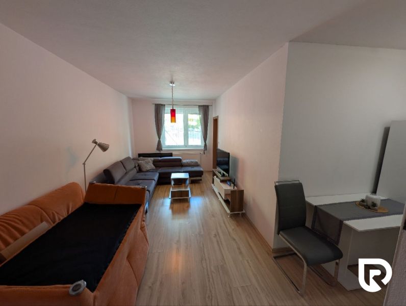 Living room in a two-room apartment with a wooden decor floor and comfortable seating.