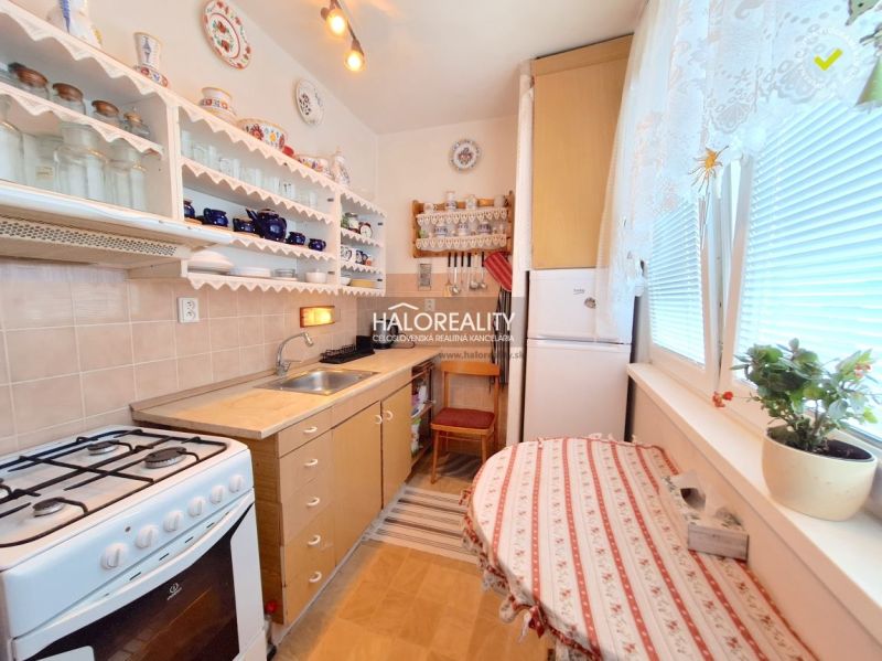 A kitchen in a 2-room apartment with wooden decor, flowers, and a dining table.