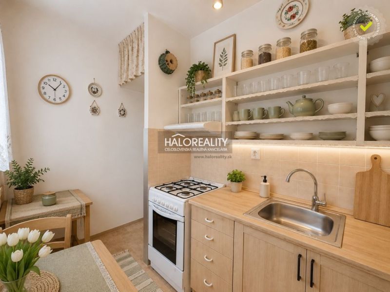 A kitchen with a gas stove, decorated shelves, and a dining table in a two-room apartment.