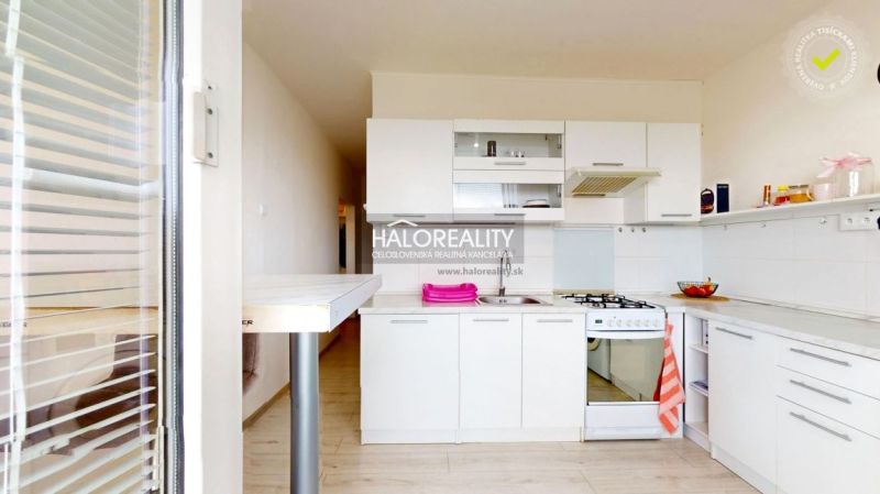 A kitchen in a 2-room apartment with white cabinets, a gas stove, and a floor with a wood design.