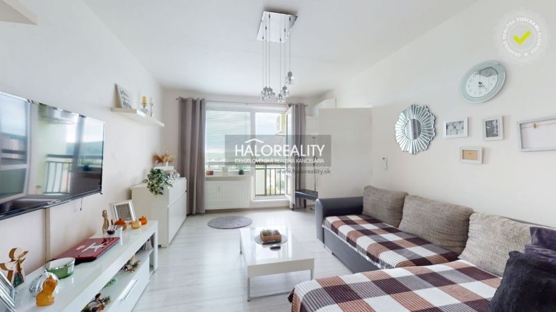 Living room in a two-room apartment with a wood-patterned floor and access to the balcony.