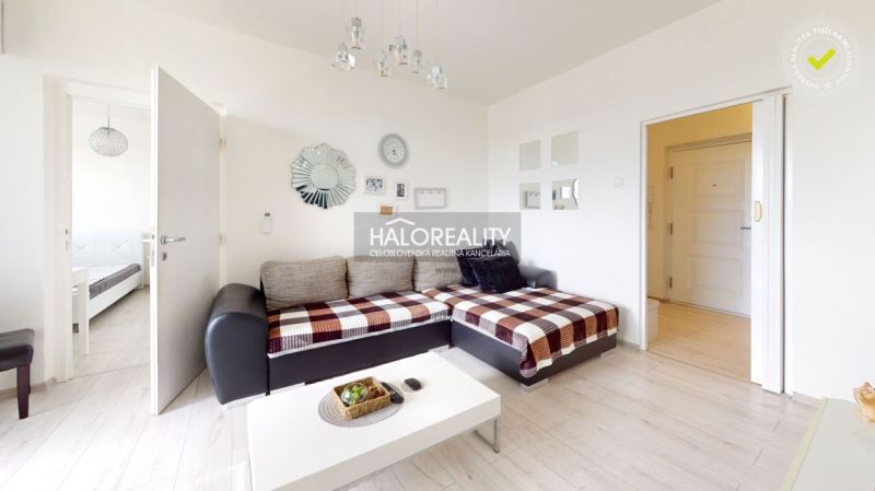 Living room in a two-room apartment with a wooden decor floor and a sofa.