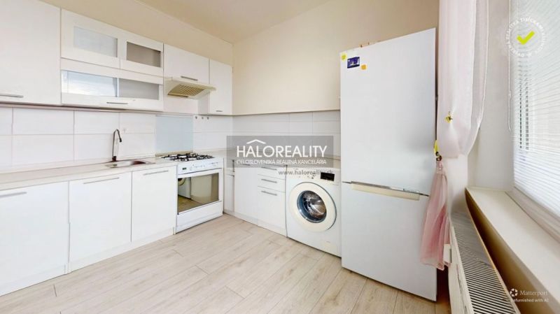 A kitchen in a 2-room apartment with white cabinets, appliances, and a floor with a wood decor.