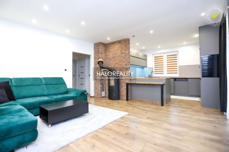Living room with a green sofa and kitchen, wooden decor flooring in a family house.