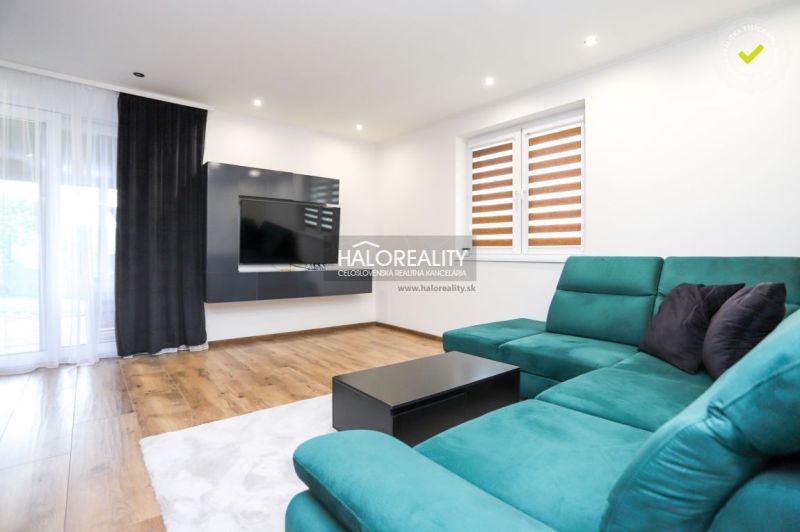 Living room with a turquoise sofa and wood-patterned flooring in a family house.