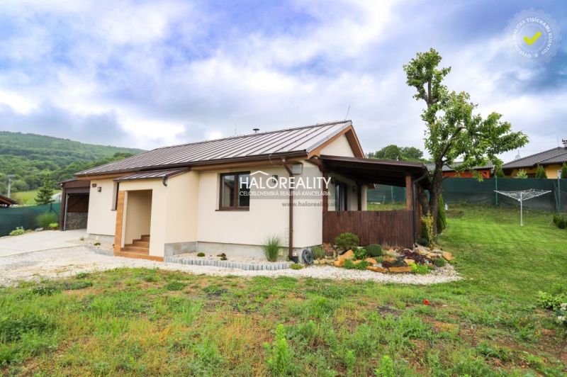 A family house in Dohňany with a lawn and a gazebo in the garden, with hills visible behind it.