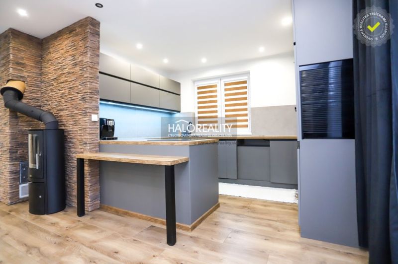 A kitchen in a family house with tiles, a gray kitchen unit, and a floor with a wooden decor.