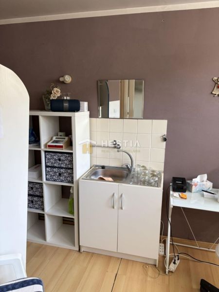A kitchenette with a sink, a shelf, and a wooden decor floor in commercial premises.