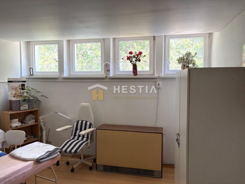 A room with a chair and a large window, commercial space with wood-patterned flooring.