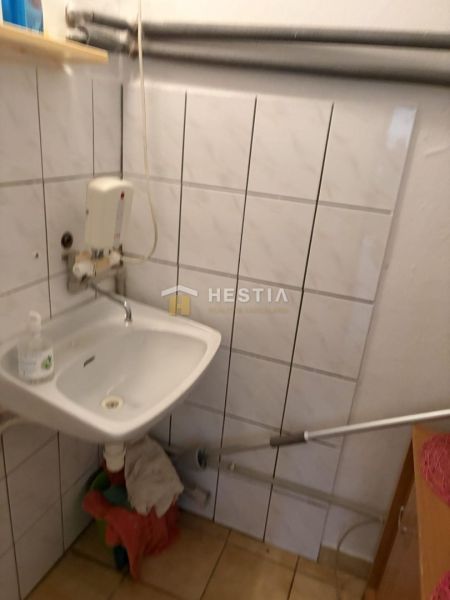 Sink, white tiles, and wall pipes in commercial premises.