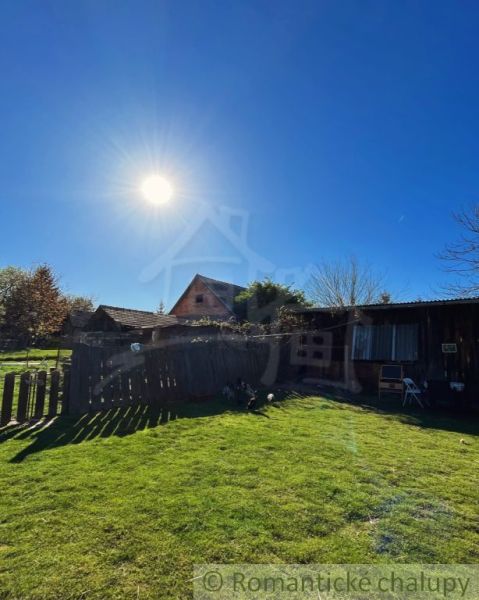 Sunny courtyard at a family house in Nové Hony with a lawn and wooden structures.