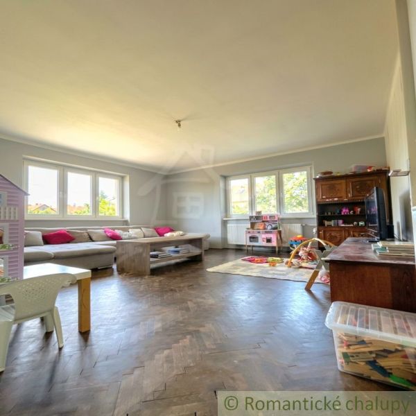 Living room in a family house with a sofa, windows, and a wooden decor floor.