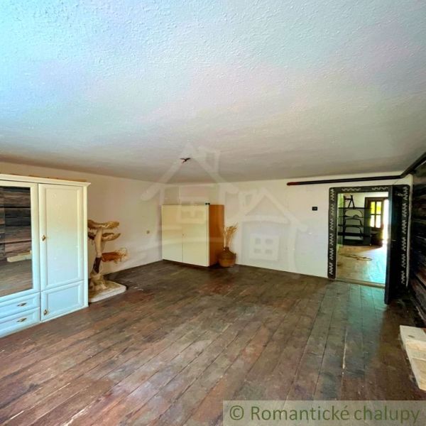 Interior of a family house with a wooden decor floor, a cabinet, and a table.