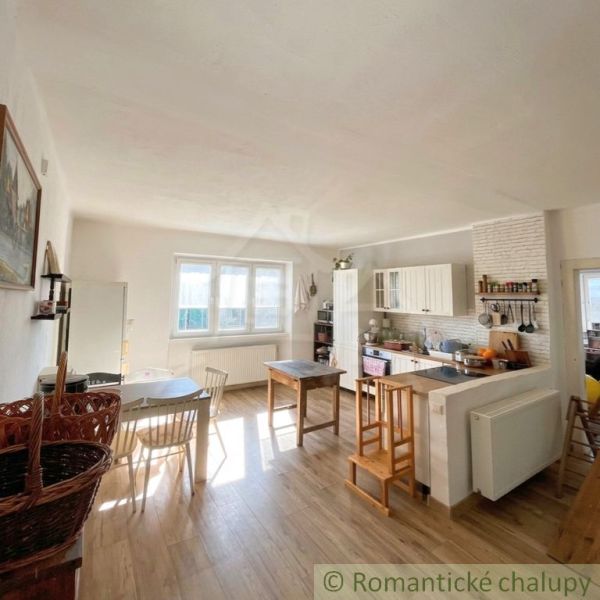 A kitchen in a family house with a wooden decor floor and white furniture.