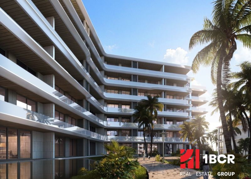 Apartment construction in Phuket with terraced balconies among palm trees and blue skies.