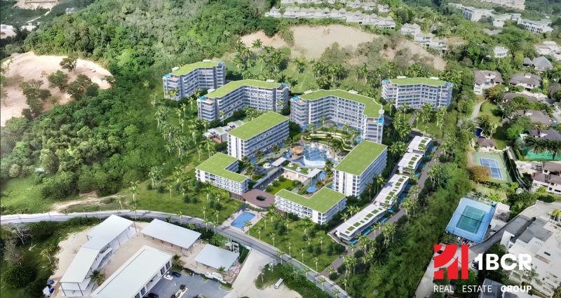 An aerial view of apartment construction in Phuket, surrounded by greenery and palm trees.
