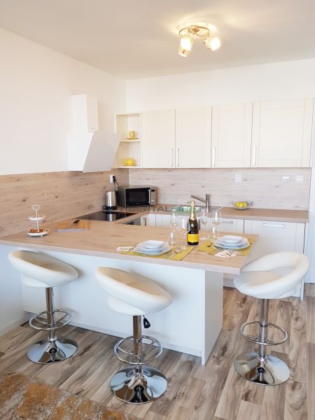 A kitchen with an island, bar stools, and a wood-patterned floor in a studio apartment.
