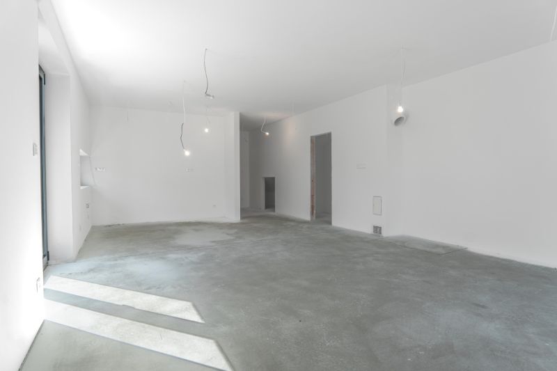 Empty room with white walls and a concrete floor in a family house.