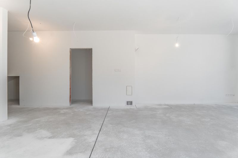 Empty room in a family house with a gray concrete floor and white walls.