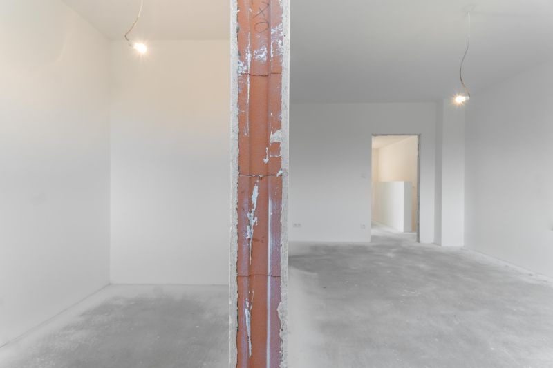 Interior of a family house with an unplastered brick wall and concrete floor in white spaces.