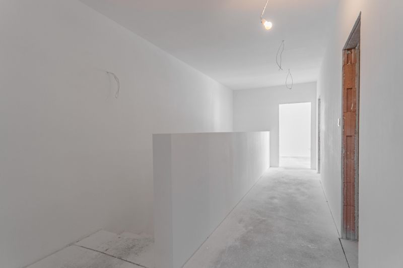 A simple white hallway in a family house with a concrete floor.