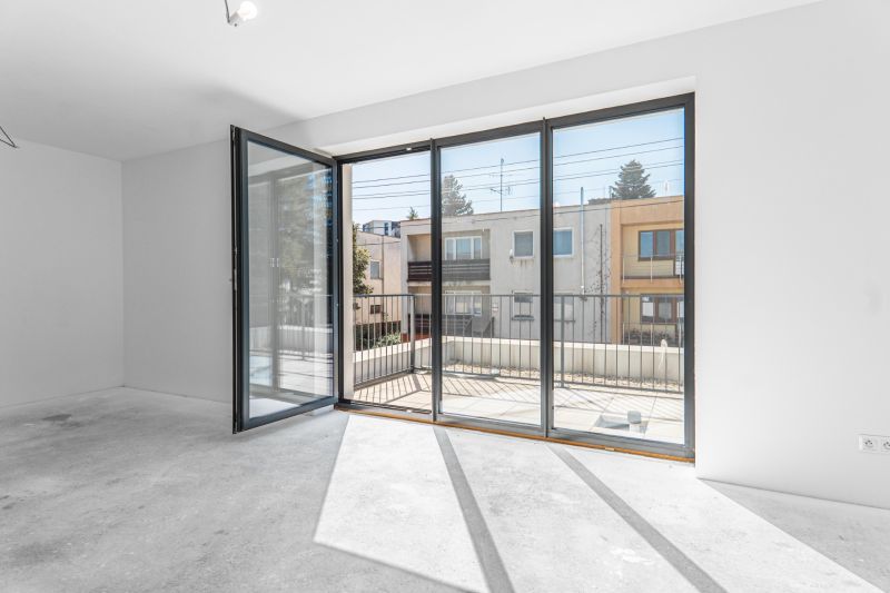 Glass doors leading to the terrace in a family house, white wall, and sunlight.