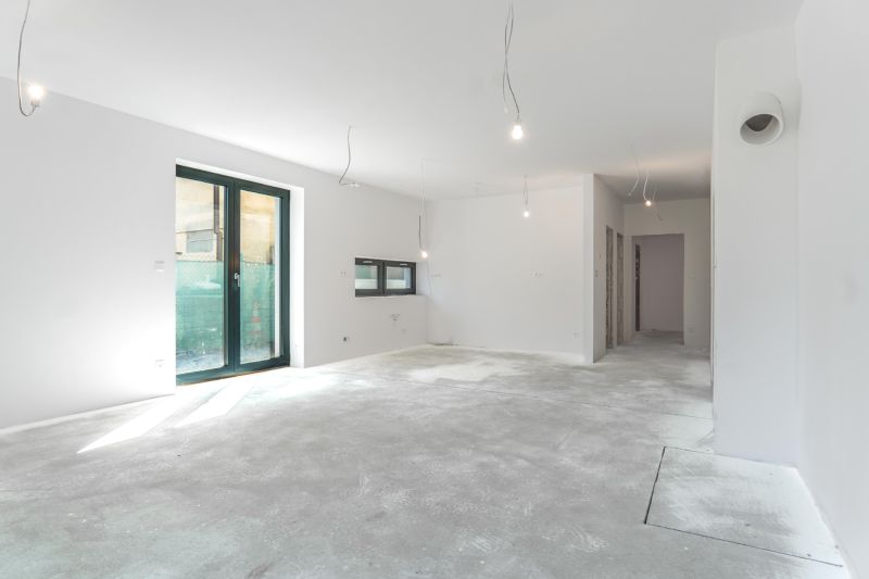 A spacious interior of a family house with large windows and a concrete floor.