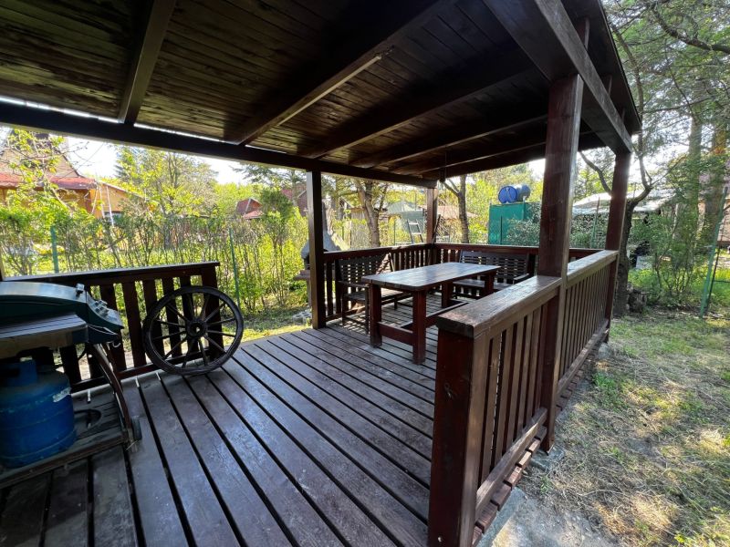 A wooden gazebo in the Gardens in Lozorno with seating, surrounded by dense vegetation.