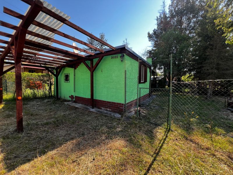 A garden cottage with a green facade and a terrace in the garden of Lozorno surrounded by trees.