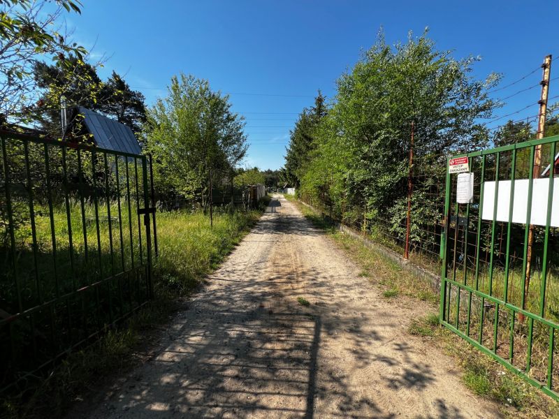 A country road leading through gardens in Lozorno, surrounded by green trees and fences.