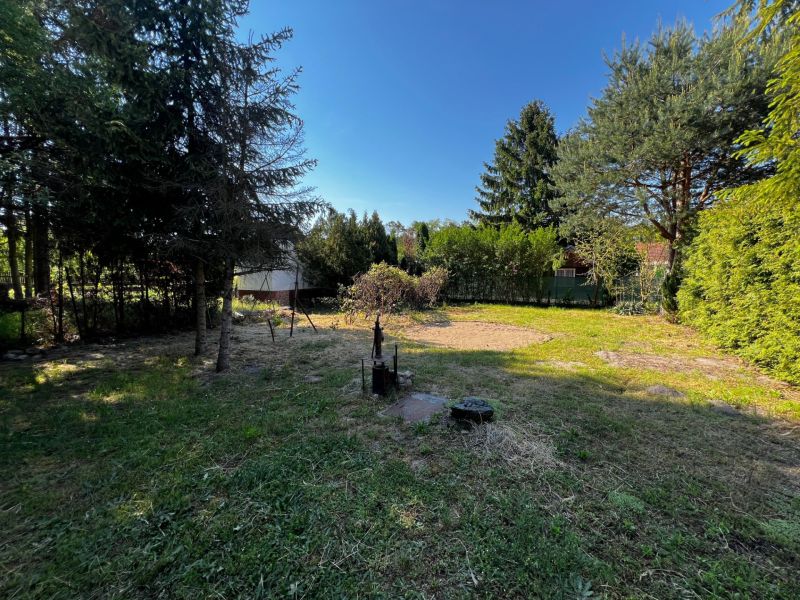 Gardens in Lozorno with lawns and trees, surrounded by a fence and shrubs.