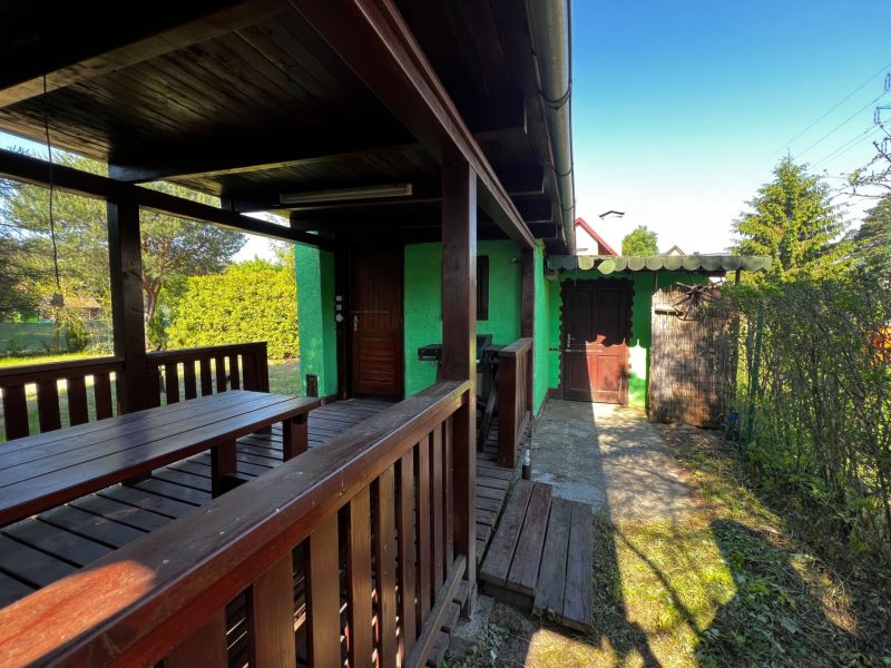 Gardens in Lozorno with a green facade of the cottage and wooden furniture on the terrace.