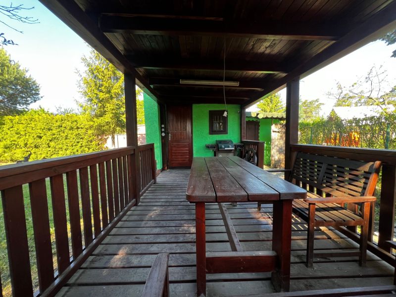 A wooden terrace with a bench and table in the gardens in Lozorno, surrounded by green shrubs.