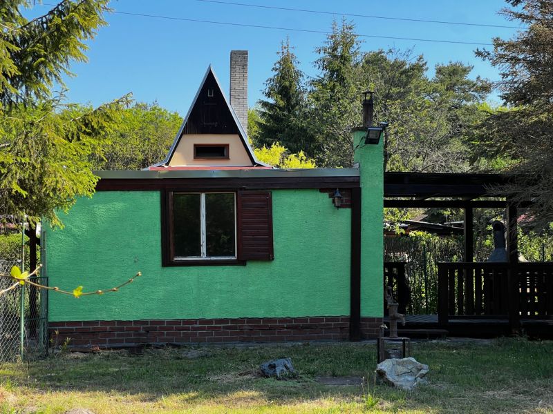 Gardens in Lozorno with a cottage in the forest, green facade, bushy tree, and gazebo.