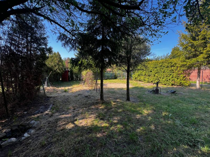 Gardens in Lozorno with a grassy area, trees, and a red garden house.