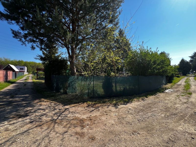 A dirt road and trees surround gardens in Lozorno under a blue sky.