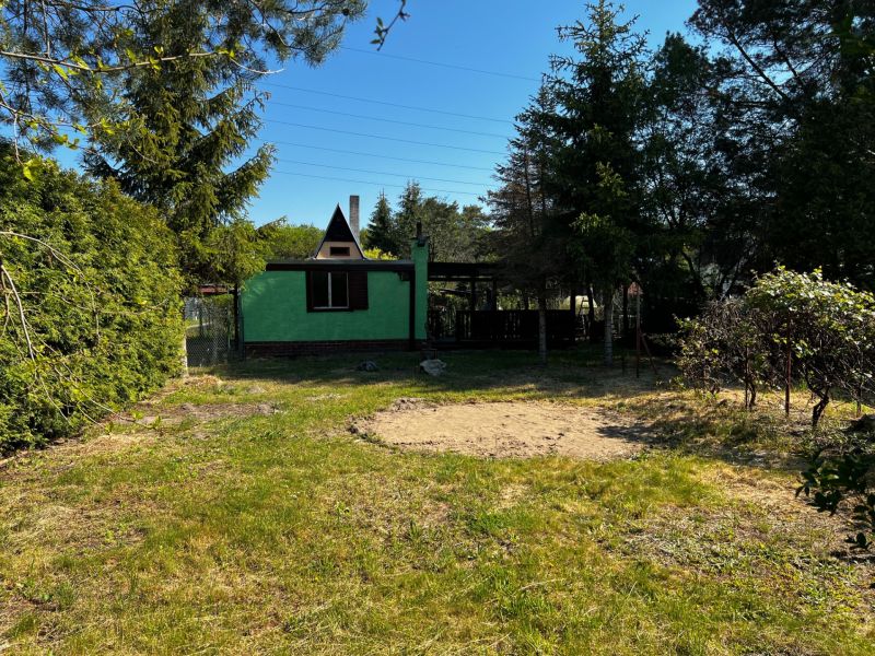 A garden in Lozorno with a cottage surrounded by greenery and trees under a blue sky.