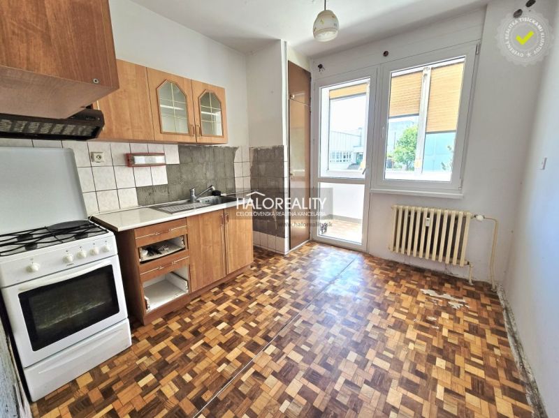 A kitchen in a 3-room apartment with a wooden decor floor and access to a balcony.