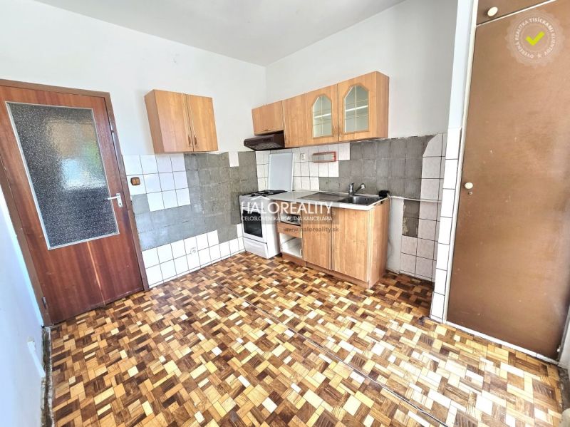 A kitchen in a 3-room apartment with a wooden decor floor and wooden cabinets.