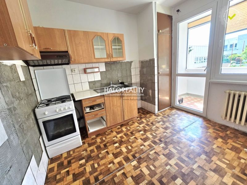 A kitchen with a gas stove and a wooden decor floor in a 3-room apartment.